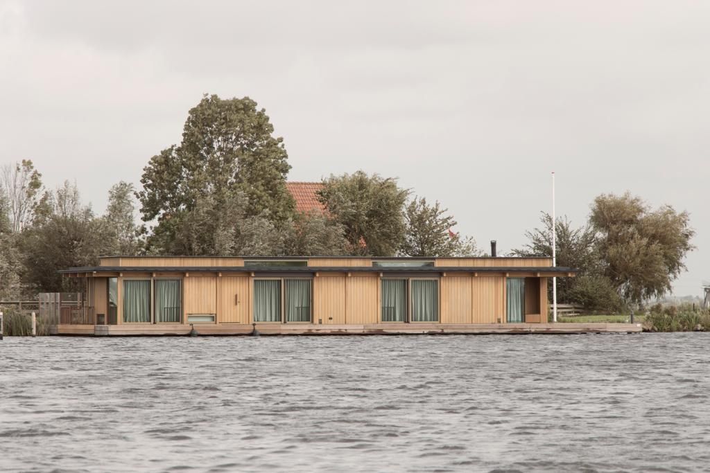 Lange, lage drijvende woning met een eiken gevel aan open water
