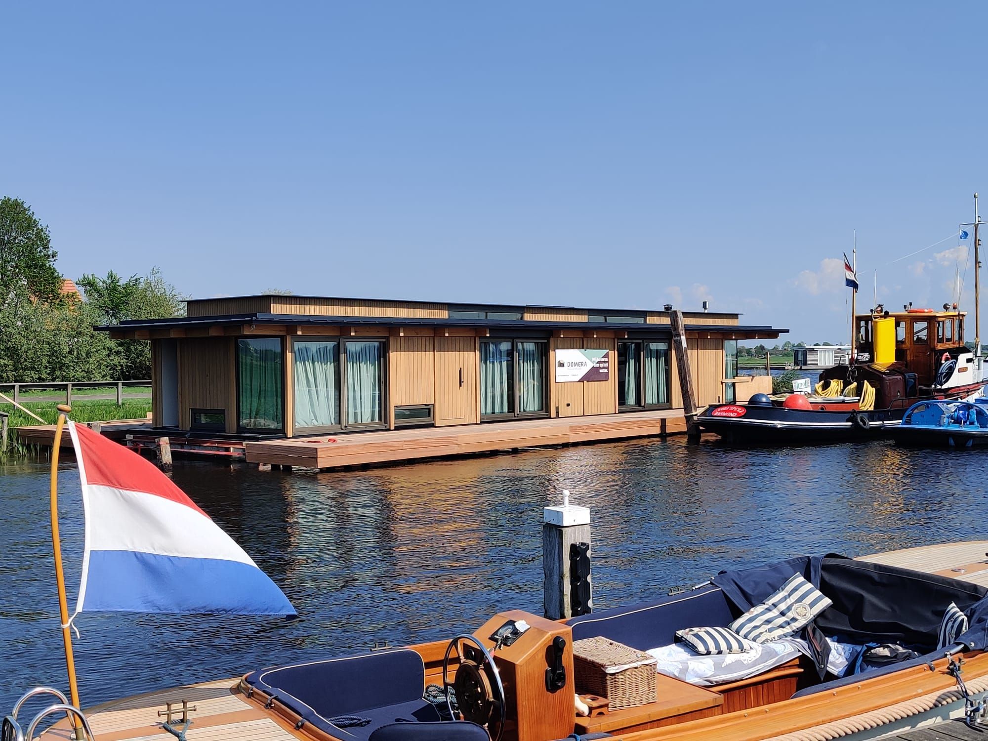 Nieuwe drijvende woning met Domera-doek aan de ligplaats, met een sloep op de voorgrond