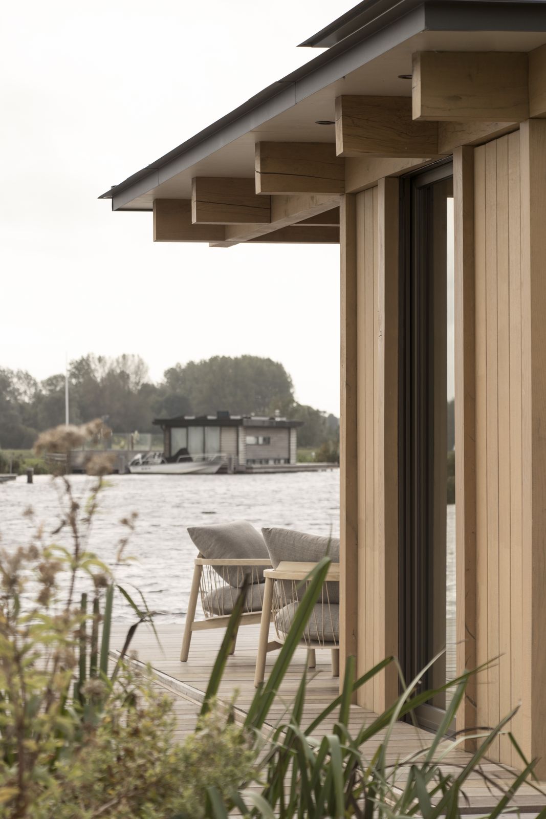 Twee stoelen op het terras onder het overstek van de eiken gevel
